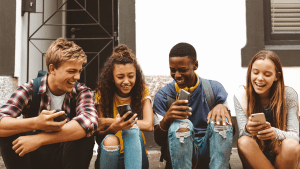 Kids using cell phones, laughing sitting on step